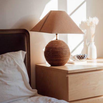 Modern home interior with bedroom setting including bedside table with lamp in sunlight